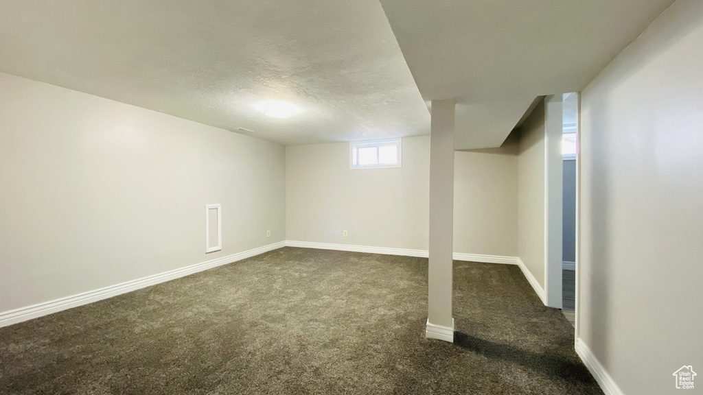 Basement featuring a textured ceiling and dark colored carpet