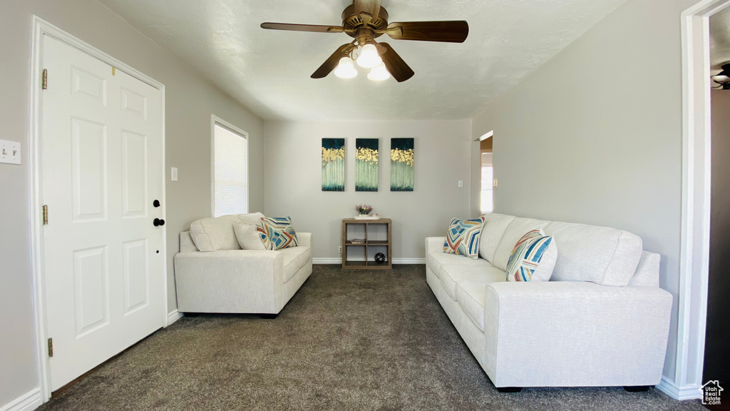 Living room featuring ceiling fan and dark carpet
