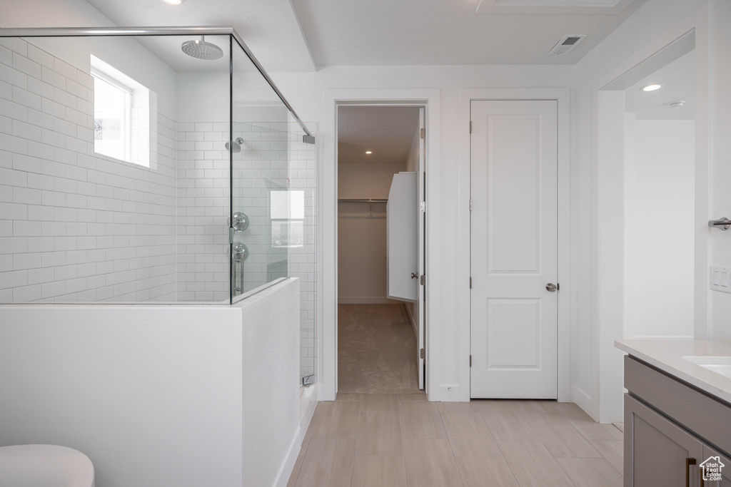 Bathroom featuring a shower with shower door, vanity, and tile floors