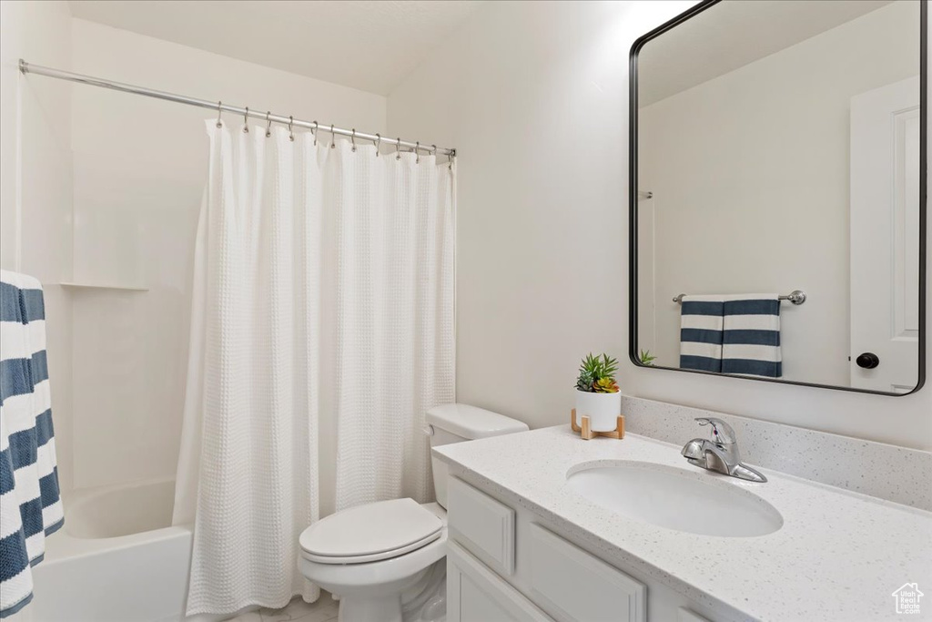 Full bathroom featuring large vanity, shower / bath combination with curtain, and toilet