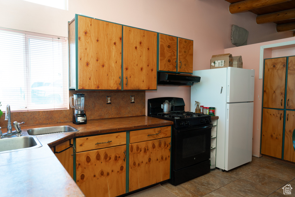 Kitchen featuring a wealth of natural light, tasteful backsplash, black gas range, and ventilation hood