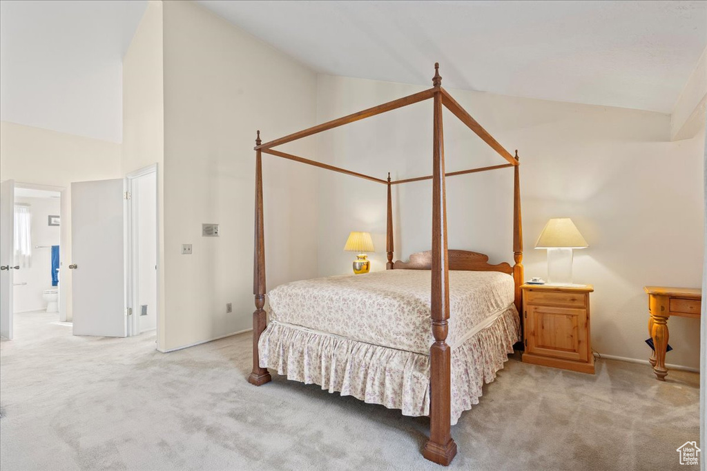 Carpeted bedroom featuring high vaulted ceiling and connected bathroom