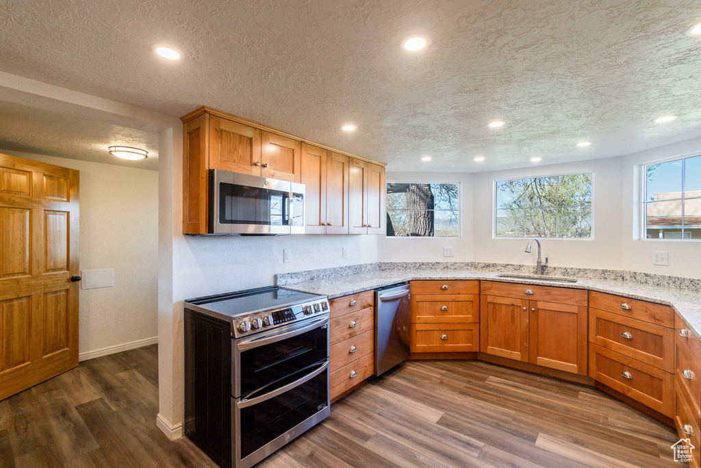 Kitchen featuring dark hardwood / wood-style floors, sink, stainless steel appliances, and light stone countertops