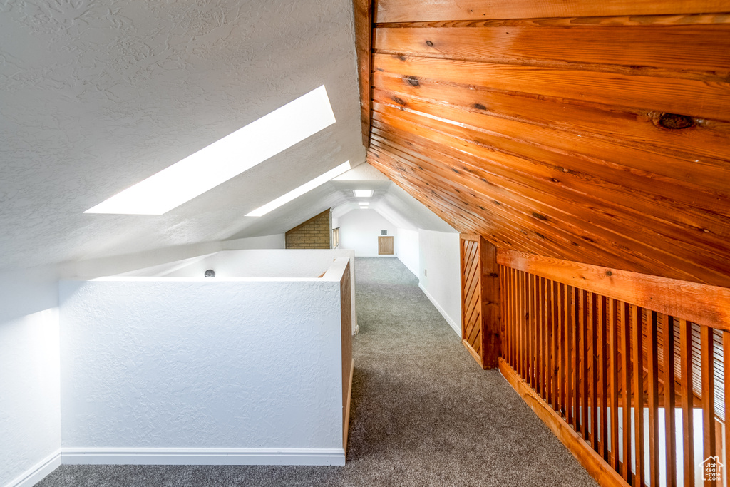 Additional living space with vaulted ceiling with skylight, dark carpet, and a textured ceiling