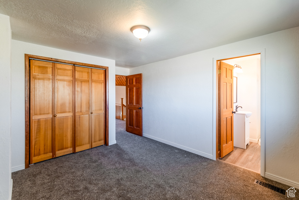 Unfurnished bedroom with a textured ceiling, a closet, carpet floors, and ensuite bathroom