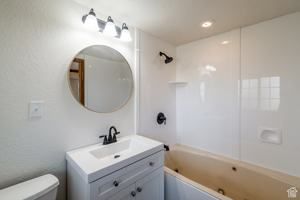Full bathroom featuring a textured ceiling, oversized vanity, toilet, and shower / washtub combination