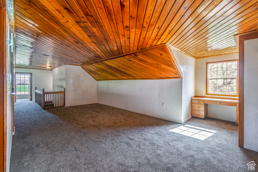 Bonus room featuring dark colored carpet, vaulted ceiling, and wood ceiling
