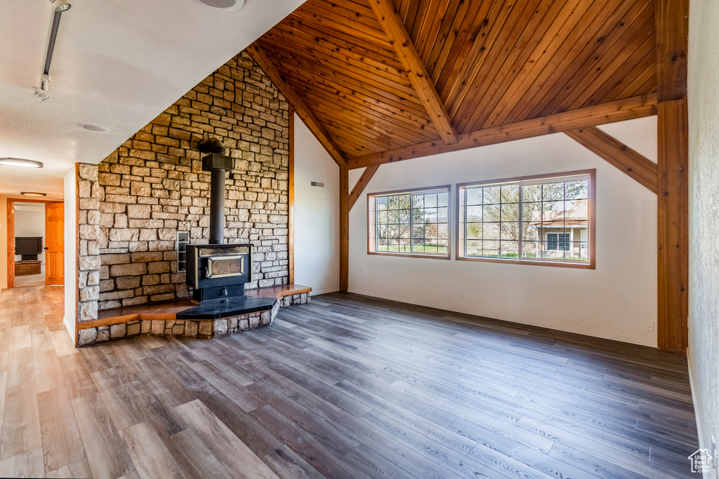 Unfurnished living room featuring a wood stove, high vaulted ceiling, wooden ceiling, hardwood / wood-style floors, and beam ceiling