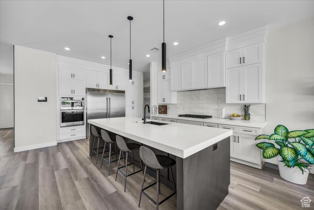 Kitchen featuring sink, light hardwood / wood-style floors, white cabinets, and backsplash