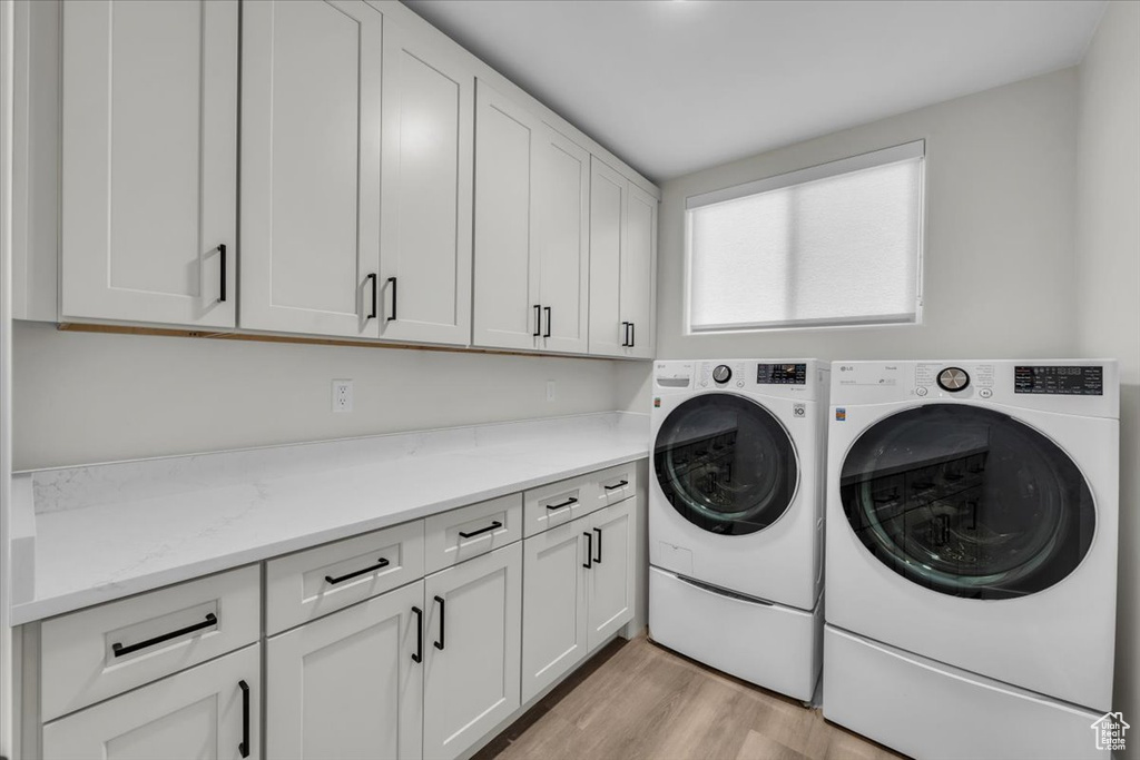 Washroom with washer and clothes dryer, cabinets, and light wood-type flooring