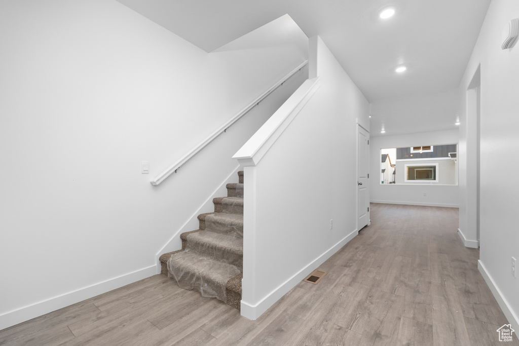 Staircase with light hardwood / wood-style floors