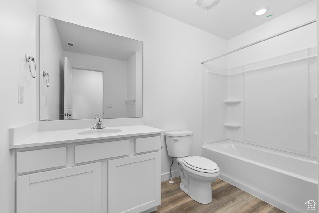 Full bathroom with hardwood / wood-style floors, vanity, toilet, and shower / washtub combination