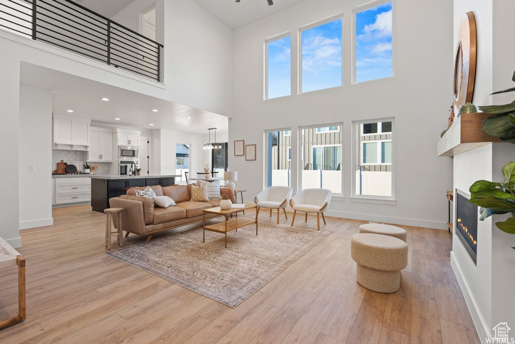 Living room featuring light hardwood / wood-style flooring, a towering ceiling, and a healthy amount of sunlight