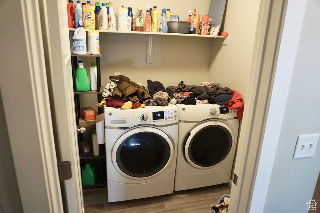 Clothes washing area with washing machine and dryer and hardwood / wood-style flooring