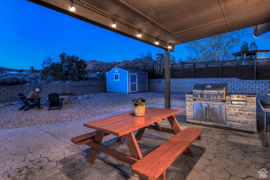 View of terrace with grilling area, a mountain view, exterior kitchen, and a storage unit