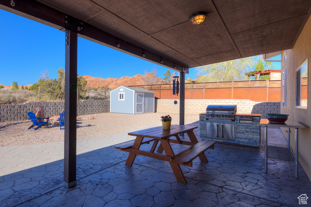View of terrace featuring an outdoor kitchen, a mountain view, a shed, and grilling area