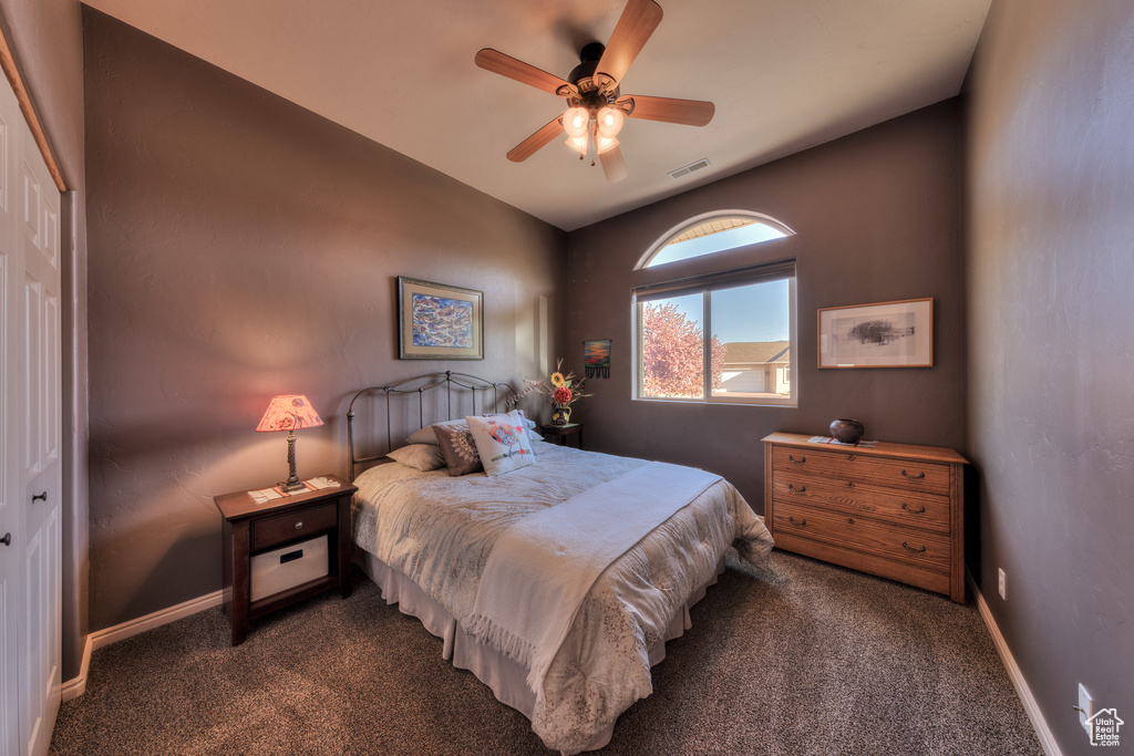 Bedroom with a closet, ceiling fan, and dark colored carpet