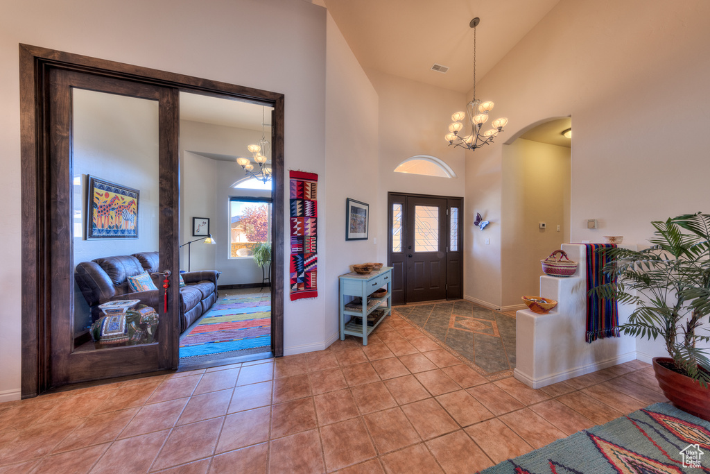 Entryway with an inviting chandelier, high vaulted ceiling, and light tile floors