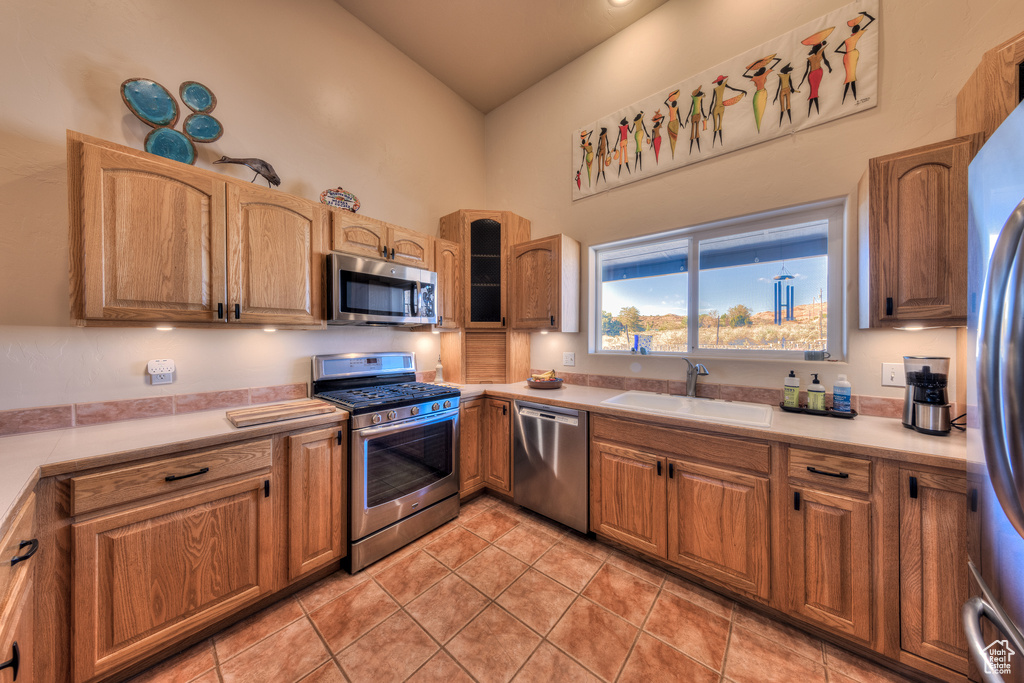 Kitchen with high vaulted ceiling, stainless steel appliances, light tile floors, and sink