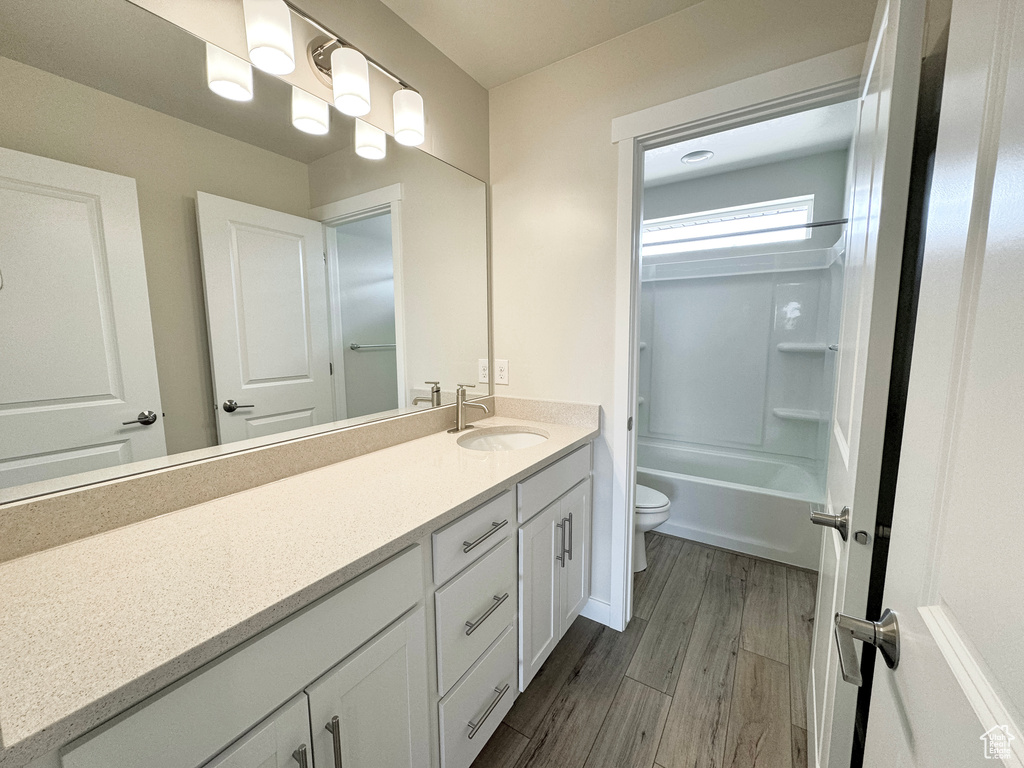 Full bathroom with washtub / shower combination, hardwood / wood-style floors, vanity, and toilet