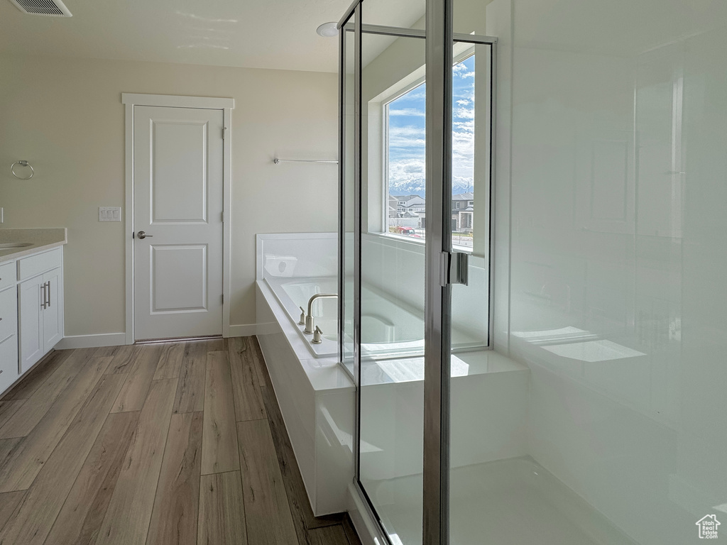 Bathroom featuring hardwood / wood-style floors, vanity, and separate shower and tub