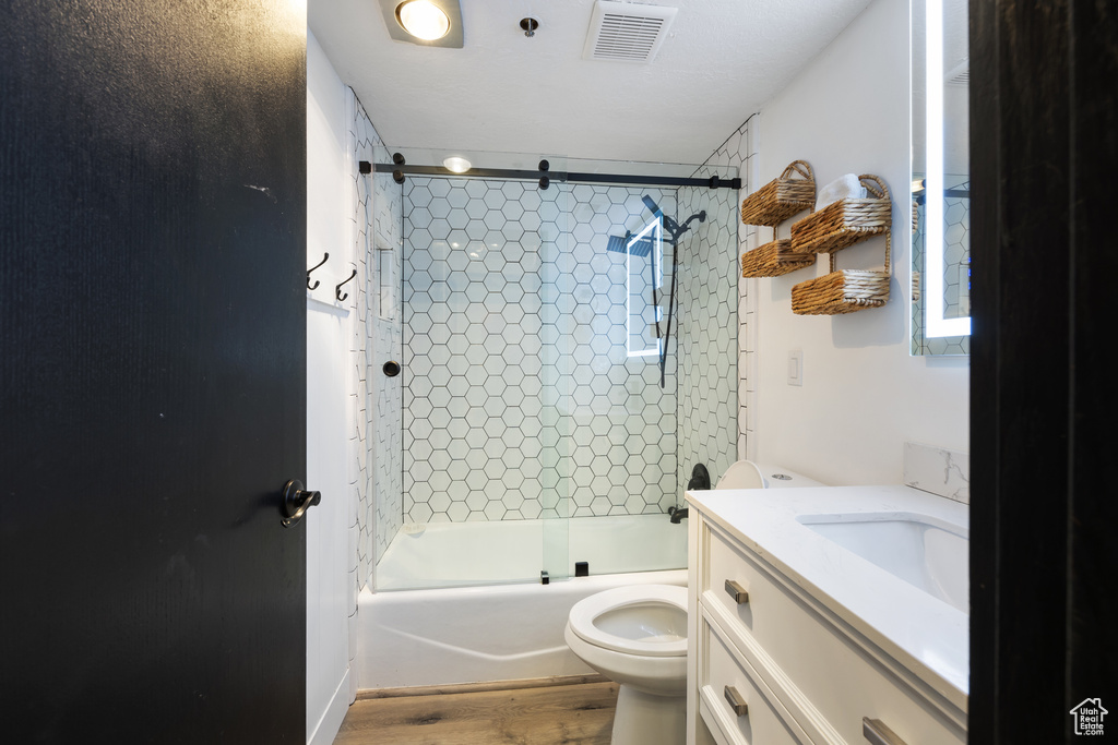 Full bathroom featuring wood-type flooring, vanity, toilet, and tiled shower / bath
