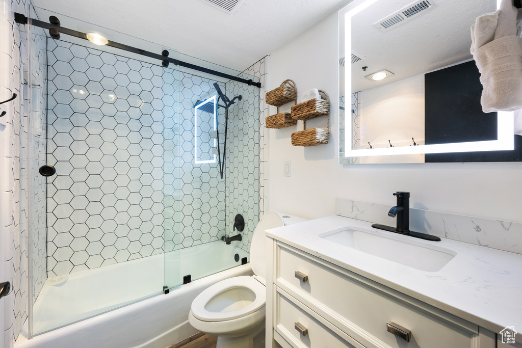 Full bathroom with toilet, oversized vanity, and shower / bath combination with glass door