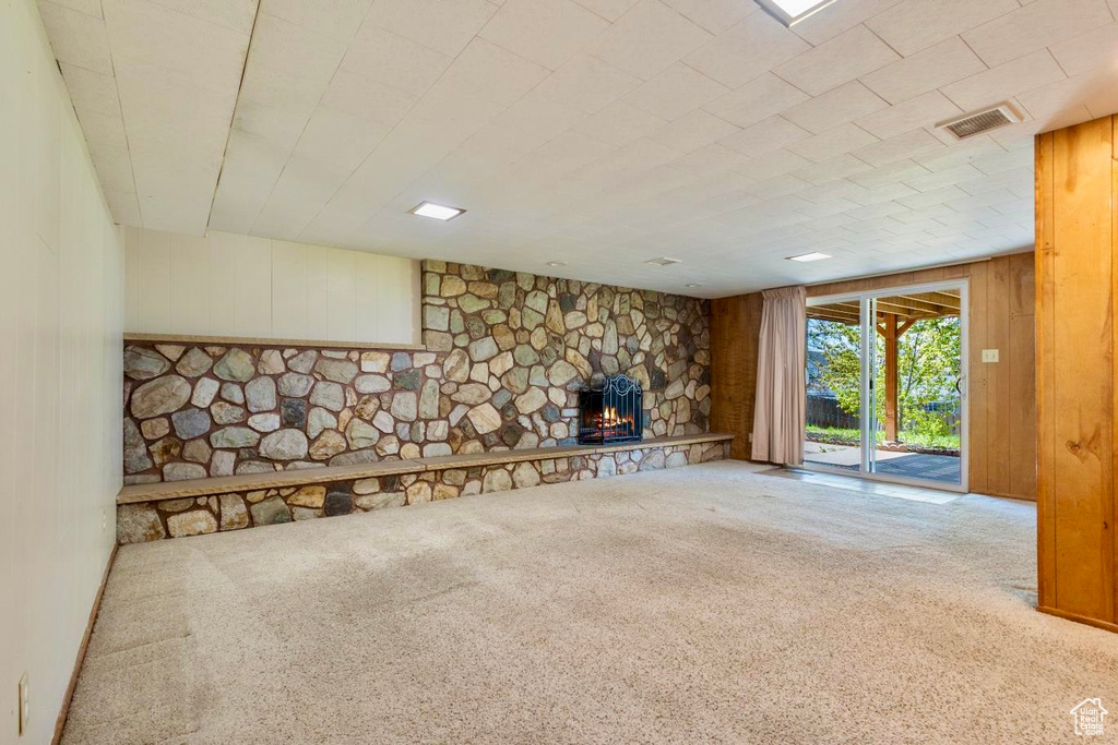 Unfurnished living room featuring wood walls, carpet, and a fireplace
