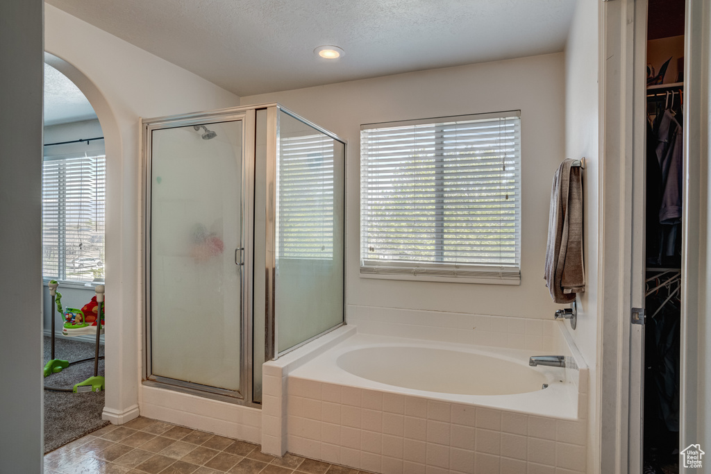 Bathroom featuring a textured ceiling, shower with separate bathtub, and tile flooring