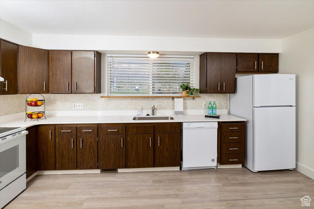 Kitchen with sink, white appliances, backsplash, dark brown cabinets, and light hardwood / wood-style flooring