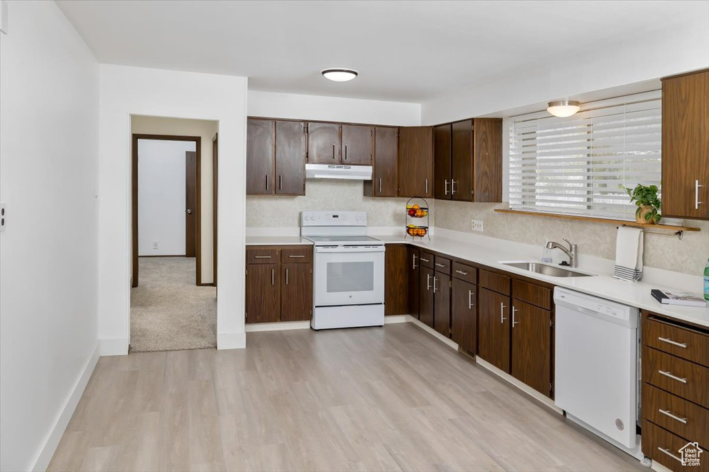 Kitchen featuring white appliances, backsplash, dark brown cabinets, sink, and light hardwood / wood-style floors