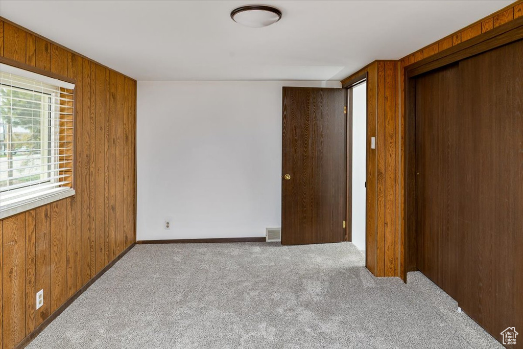 Interior space with a closet, wood walls, and carpet