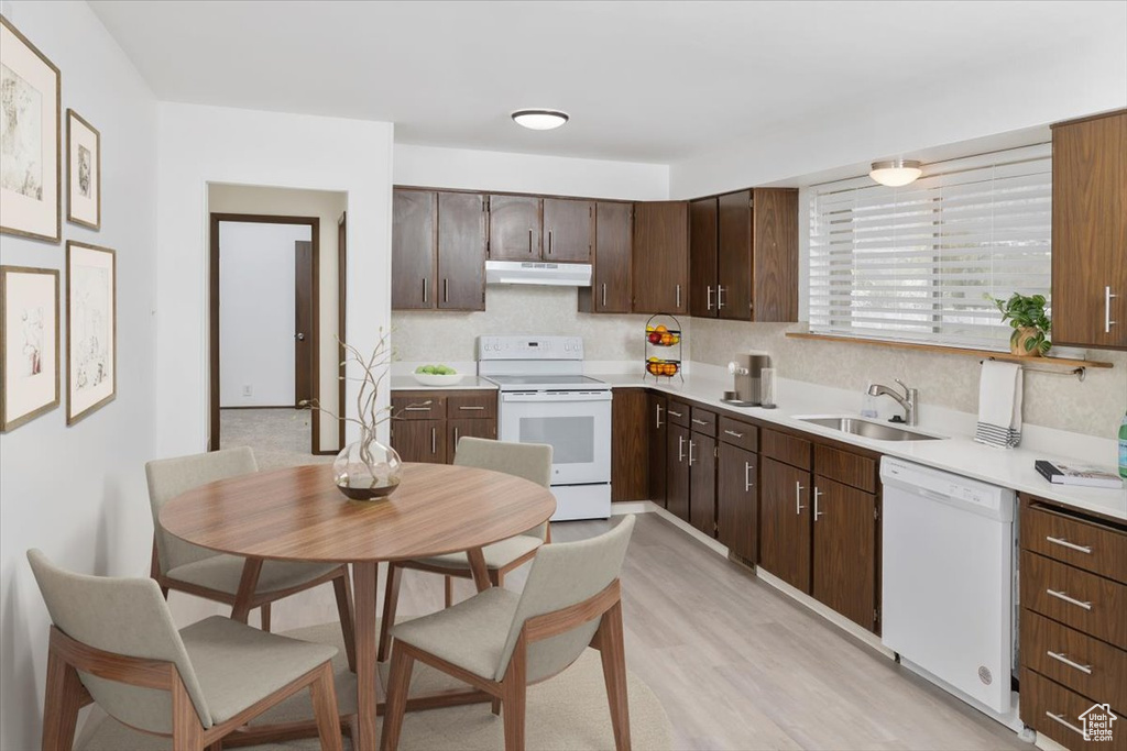 Kitchen featuring dark brown cabinets, light hardwood / wood-style flooring, white appliances, tasteful backsplash, and sink