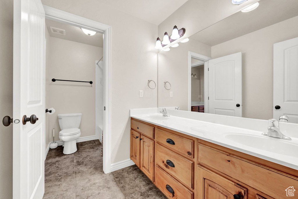 Bathroom featuring tile flooring, toilet, and dual bowl vanity