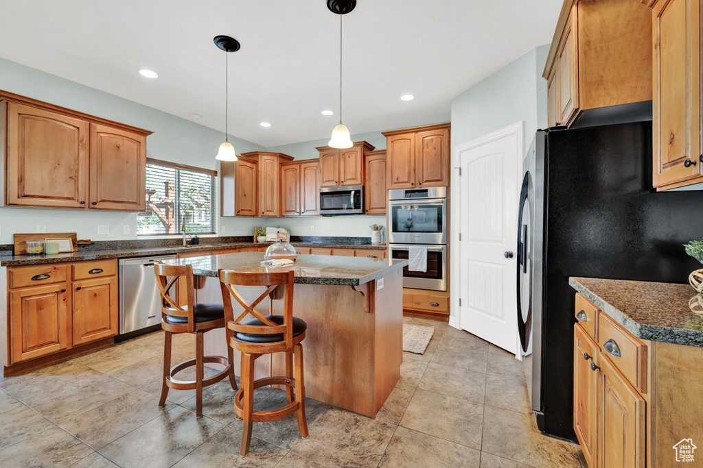 Kitchen featuring pendant lighting, appliances with stainless steel finishes, light tile floors, and a kitchen island