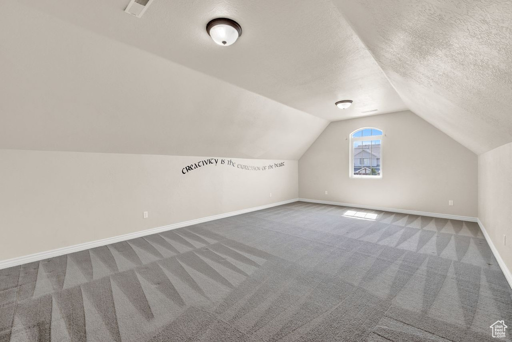 Bonus room with lofted ceiling, carpet flooring, and a textured ceiling