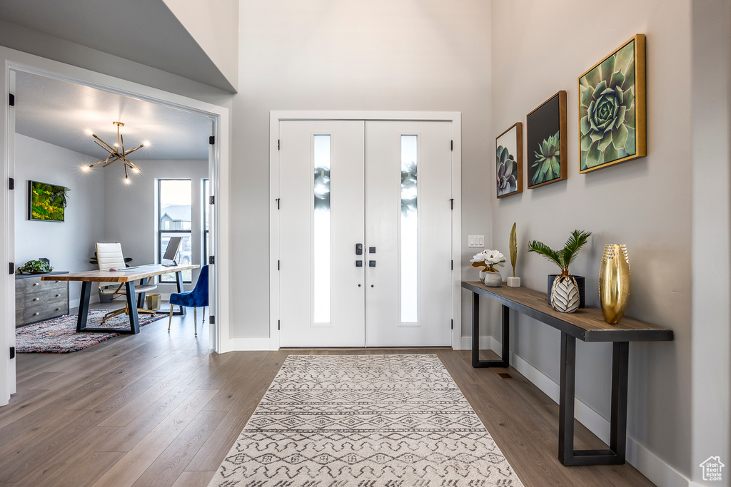 Foyer entrance featuring french doors, dark wood-type flooring, and an inviting chandelier