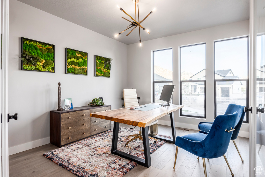 Office featuring a wealth of natural light, light hardwood / wood-style floors, and a notable chandelier