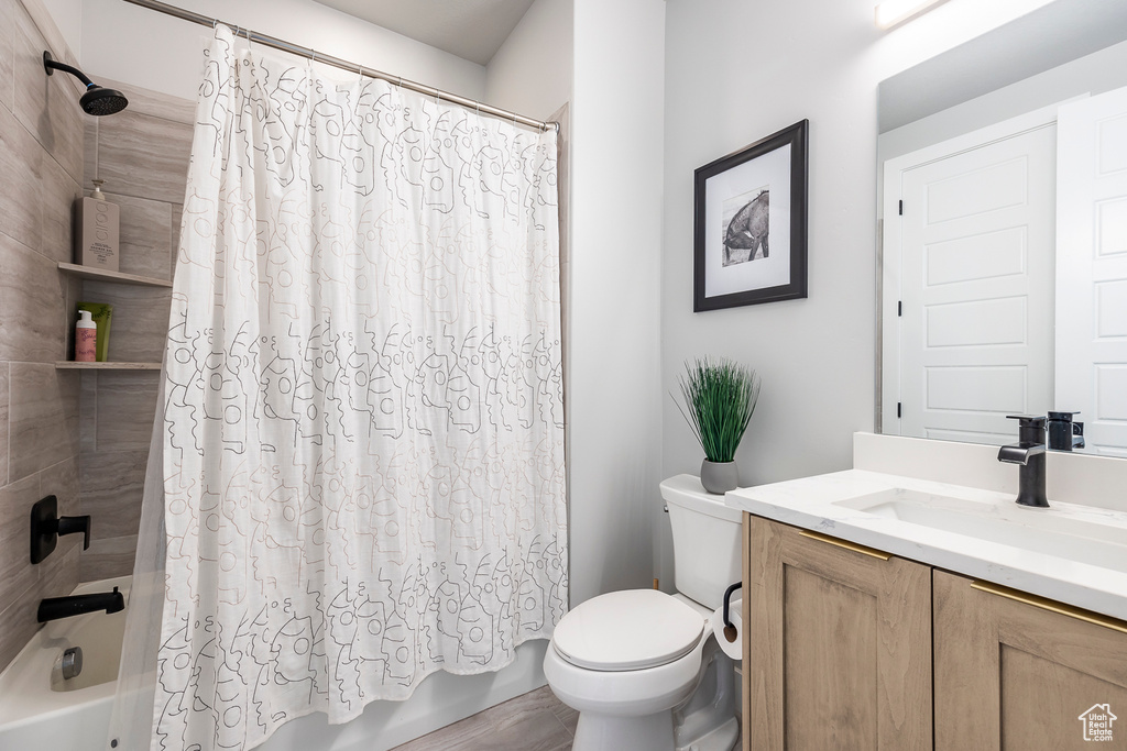 Full bathroom with vanity, toilet, and shower / bath combo with shower curtain