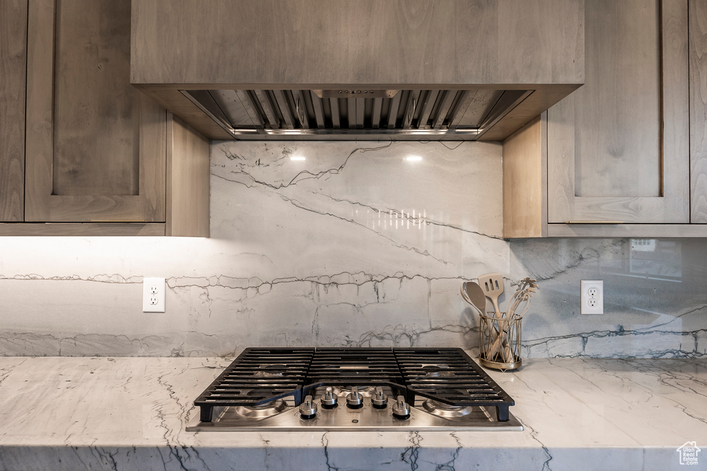 Kitchen featuring backsplash, custom range hood, and stainless steel gas cooktop