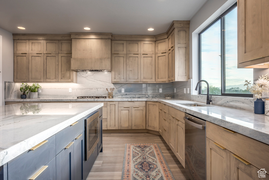 Kitchen featuring appliances with stainless steel finishes, a healthy amount of sunlight, light hardwood / wood-style flooring, and custom range hood