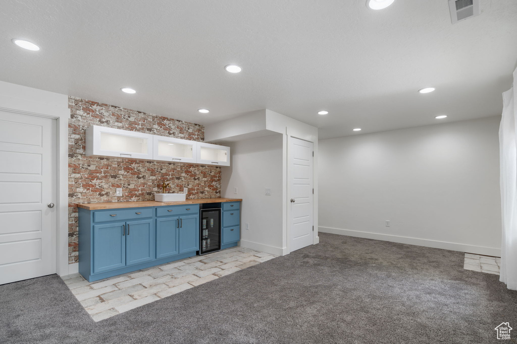 Kitchen with wine cooler, backsplash, butcher block countertops, light colored carpet, and blue cabinets