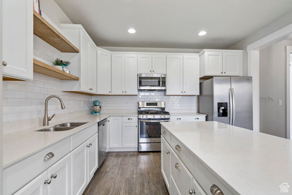 Kitchen featuring sink, tasteful backsplash, white cabinetry, dark hardwood / wood-style flooring, and stainless steel appliances
