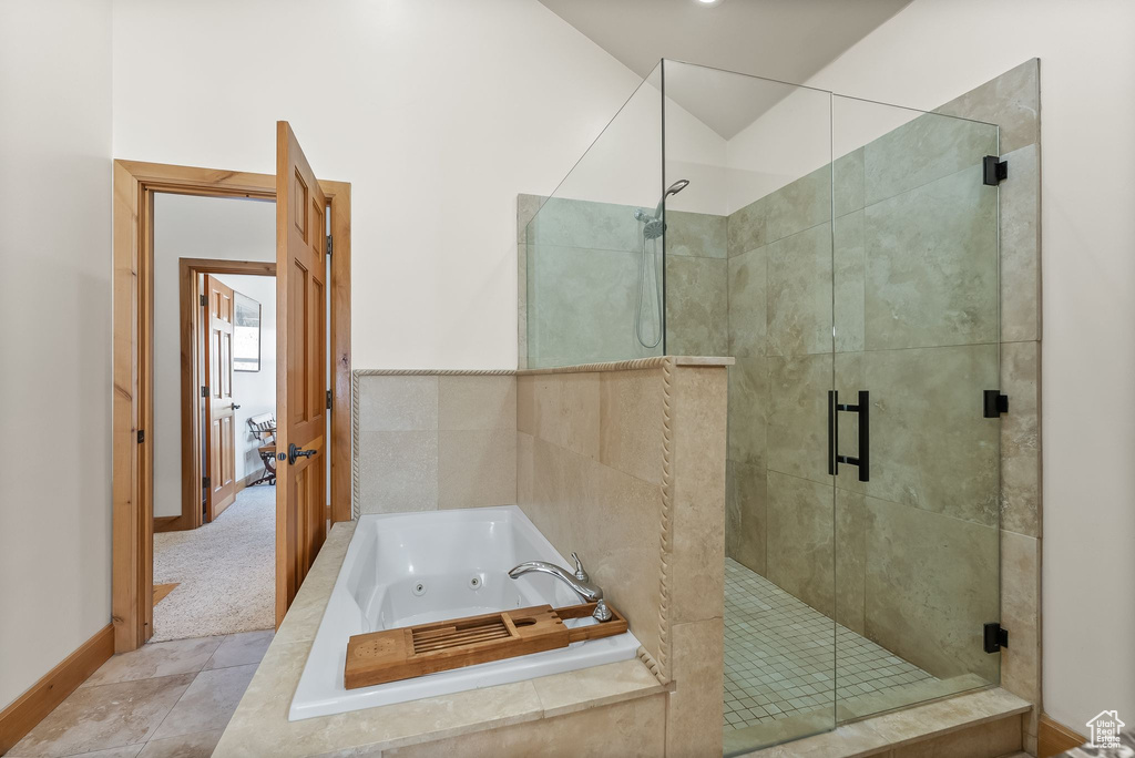 Bathroom featuring shower with separate bathtub and tile flooring