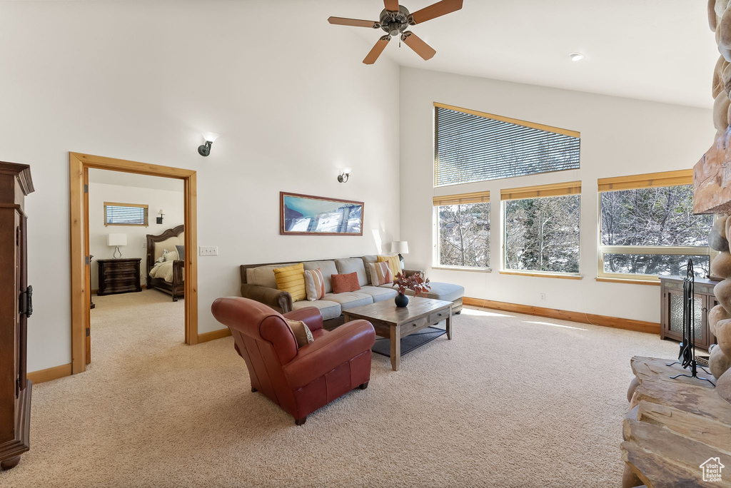 Carpeted living room featuring high vaulted ceiling, ceiling fan, and a healthy amount of sunlight
