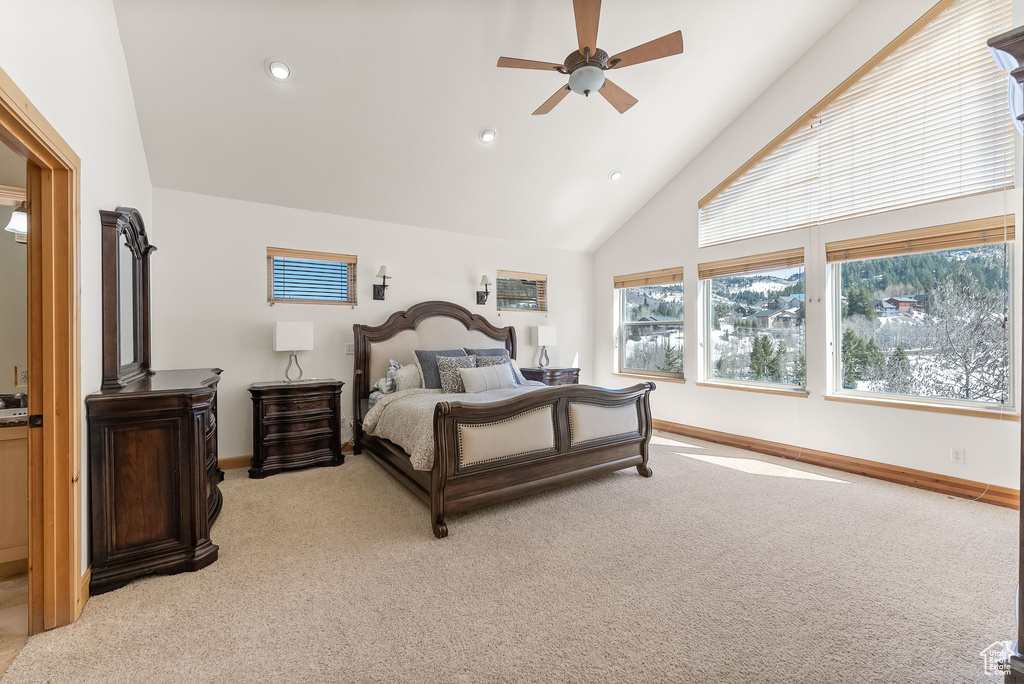 Bedroom with high vaulted ceiling, ceiling fan, carpet flooring, and a wood stove