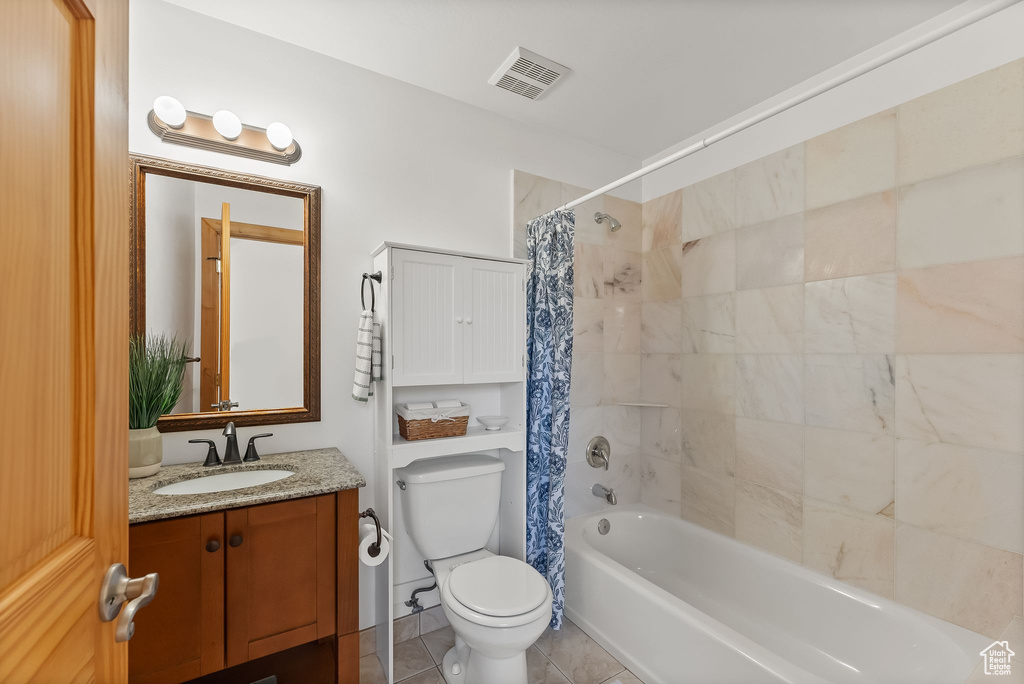 Full bathroom featuring tile flooring, vanity, toilet, and shower / bathtub combination with curtain