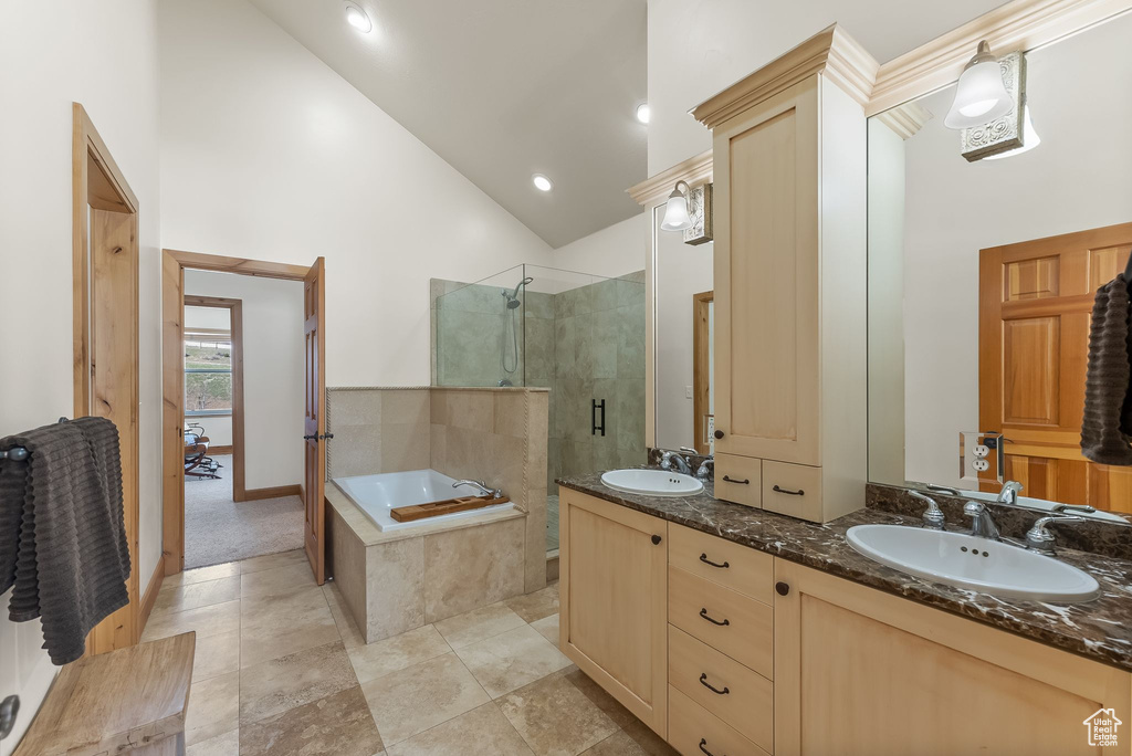 Bathroom with high vaulted ceiling, tile flooring, separate shower and tub, and dual vanity