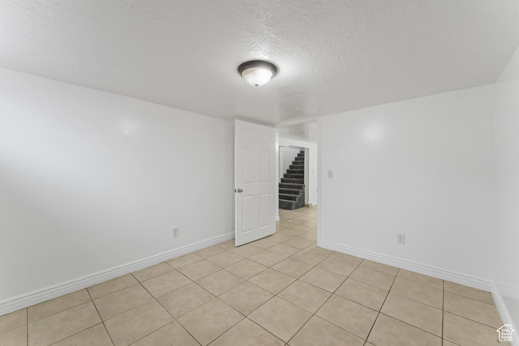Empty room featuring light tile floors and a textured ceiling