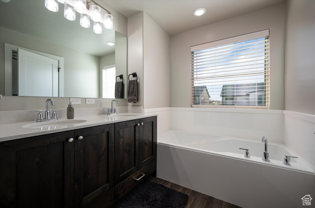 Bathroom with a healthy amount of sunlight, a bathing tub, hardwood / wood-style floors, and dual vanity